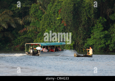 Touristenboot geht Dorfbewohner im Kanu am natürlichen Regenwald-Kanal. Tortuguero Nationalpark. Costa Rica. Oktober 2011. Stockfoto