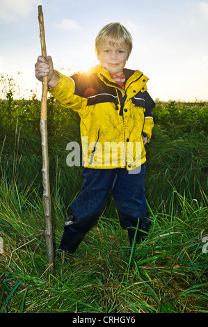 Junge, Schlamm, posiert mit einem Stock auf ein Herbstnachmittag in einer ländlichen Umgebung, Stockfoto