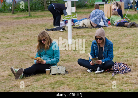 Zwei junge Frauen, die Bücher zu lesen saß auf Rasen an den Telegraph Hay Festival 2012, Hay-on-Wye, Powys, Wales, UK Stockfoto