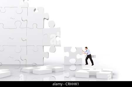 junger Mann, ein riesiges Puzzle-Stück in riesigen Puzzle Wand passt Klein Flottbek Stockfoto