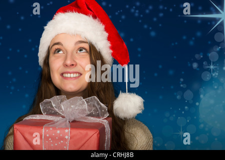 Junge Frau trägt Weihnachtsmütze, hält Weihnachten vorhanden, Porträt Stockfoto