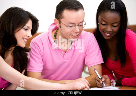 männliche Schüler sitzen und arbeiten zusammen mit zwei schönen jungen Studentinnen Stockfoto