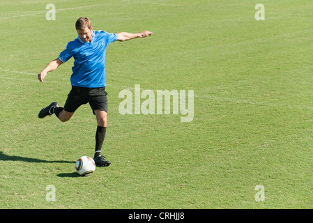 Fußball-Spieler treten Fußball auf Fußballplatz Stockfoto