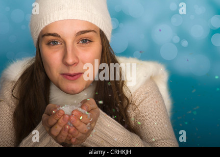 Junge Frau trägt Winterbekleidung, hält Handvoll Konfetti, Porträt Stockfoto