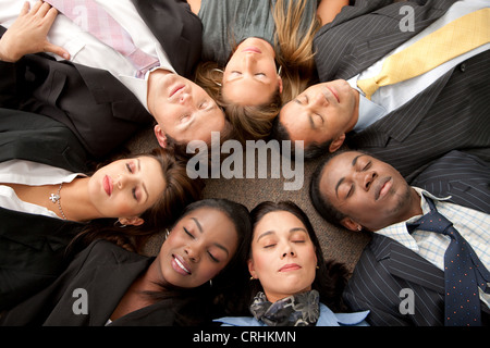 Unternehmensgruppe mit Köpfen zusammen auf dem Boden und ihre Augen geschlossen in einem Büro Stockfoto