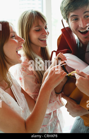 Frauen greifen Geschenktüten in armen Mannes Stockfoto