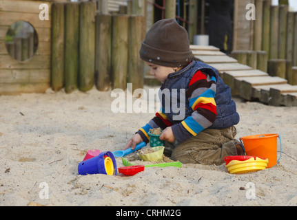 kleiner Junge spielt in einem Sandkasten mit Sand Formen Stockfoto