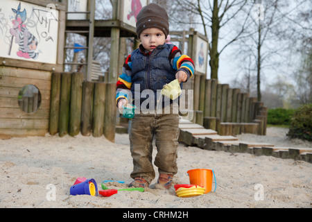 kleiner Junge spielt in einem Sandkasten mit Sand Formen Stockfoto