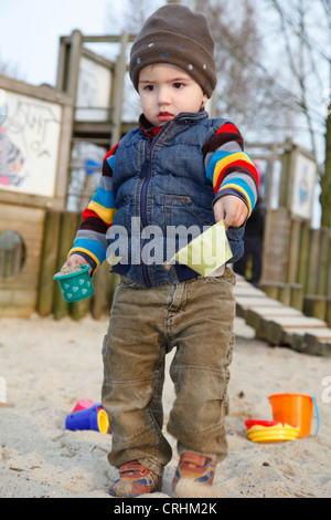 kleiner Junge spielt in einem Sandkasten mit Sand Formen Stockfoto