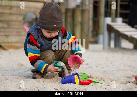 kleiner Junge spielt in einem Sandkasten mit Sand Formen Stockfoto