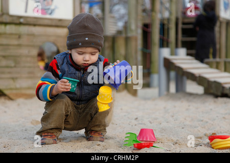 kleiner Junge spielt in einem Sandkasten mit Sand Formen Stockfoto