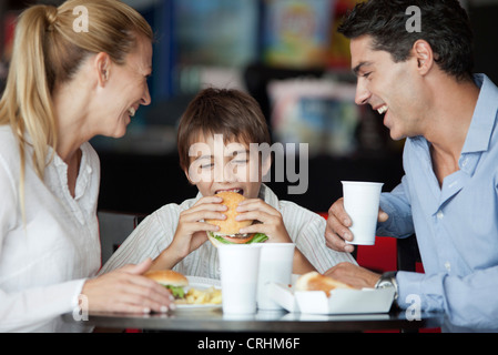 Junge Hamburger Essen in Fast-Food-Restaurant mit seinen Eltern Stockfoto