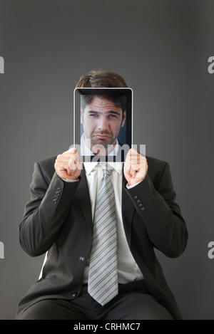 Mann, stirnrunzelnd Foto vor sein Gesicht hält Stockfoto