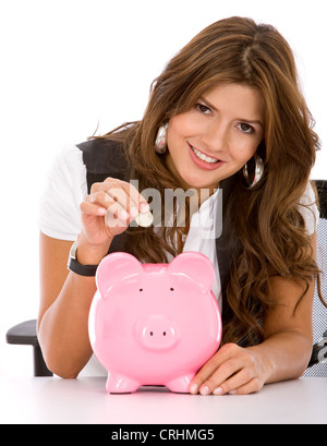 schöne Geschäftsfrau, etwas Geld für ihre Ersparnisse in ein rosa Sparschwein Stockfoto