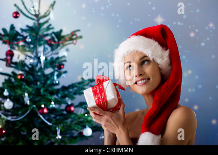 Frau trägt Weihnachtsmütze, schütteln Weihnachtsgeschenk Stockfoto