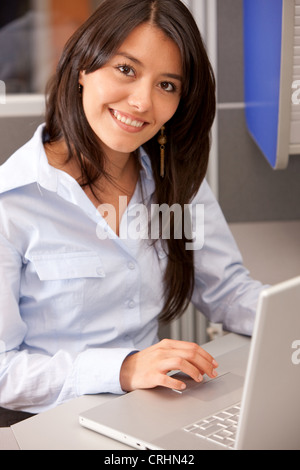 Business-Frau an einem Laptop arbeiten und lächelnd in einem Büro Stockfoto