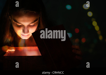 Junge Frau von Licht von innen Geschenkbox beleuchtet Stockfoto