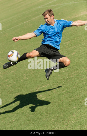 Fußball-Spieler treten Ball in der Luft Stockfoto