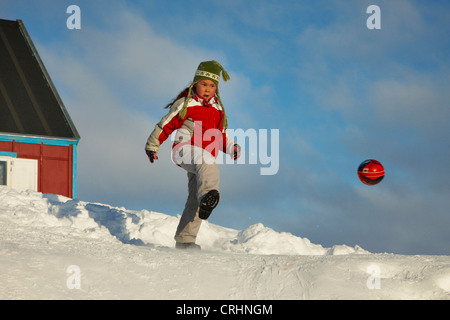 Mädchen mit Ball im Schnee, Grönland, Ostgroenland, Tunu, Kalaallit Nunaat, Scoresbysund, Kangertittivag, Ittoqqortoormiit Stockfoto