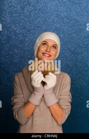 Frau trägt zu stricken, Mütze und Handschuhe vor verschneiten Hintergrund, Porträt Stockfoto