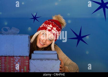 Junge Frau hinter gestapelten Weihnachten Geschenke, Porträt Stockfoto