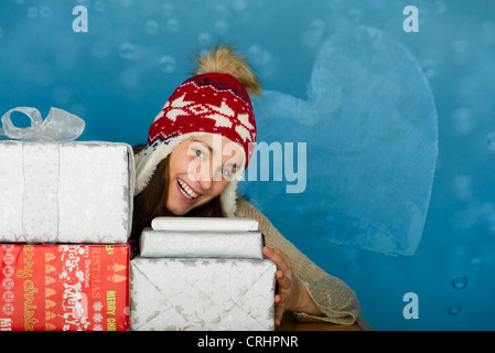 Junge Frau mit Stapeln von Weihnachtsgeschenken, Porträt Stockfoto