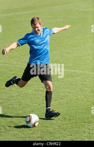 Fußball-Spieler treten Fußball auf Fußballplatz Stockfoto