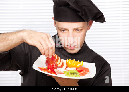 Koch in schwarzer Uniform dekorieren leckere Obstteller Stockfoto
