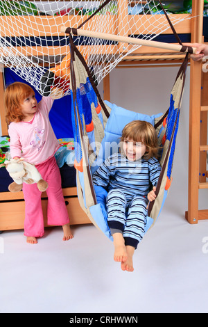 kleinen Jungen und Mädchen im Schlafanzug in einem Schwung von Billi-Bolli Hochbett Stockfoto
