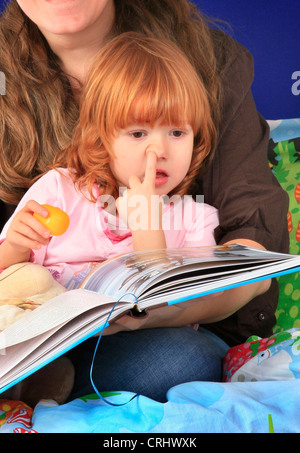 Kleine rothaarige Mädchen eine Gutenachtgeschichte sammeln ihre Nase anhören Stockfoto