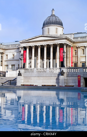 Vorderansicht von der National Gallery London, spiegelt sich in das Stille Wasser aus einem Brunnen Pool, Trafalgar Square, am frühen Morgen. Stockfoto