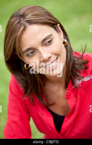 lächelnde Frau in einem roten Bluse auf einer Wiese Stockfoto