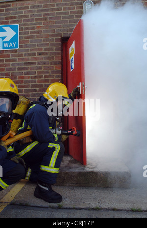 Feuerwehrleute, die das Öffnen einer Tür, löschte das Feuer Stockfoto