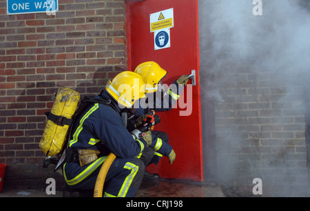 Feuerwehrleute, die das Öffnen einer Tür, löschte das Feuer Stockfoto