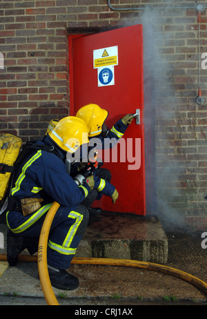 Feuerwehrleute, die das Öffnen einer Tür, löschte das Feuer Stockfoto