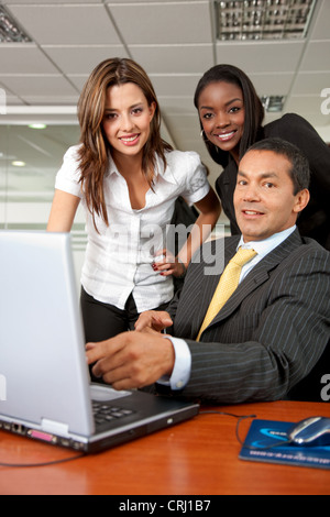 drei Geschäftsleute versammelten sich vor einem Laptop im Büro mit einem Lächeln Stockfoto