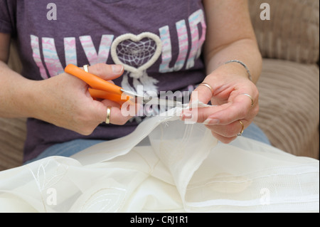 Saiten auf Überschrift Band geschnitten bevor Überschrift Band auf Voile Vorhänge gezogen werden können Stockfoto