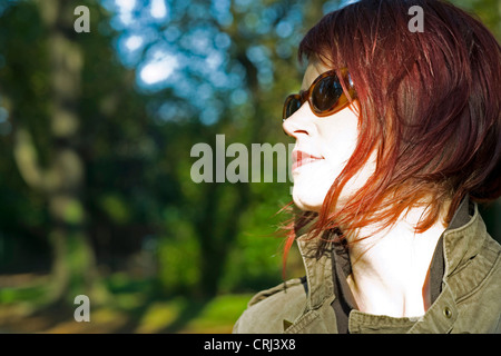 Junge, rote kurzhaarige Frau mit Sonnenschirmen im Herbst Stockfoto