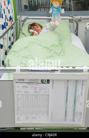 10 Jahre alter Junge liegen in einem Bett aus einem Kinderkrankenhaus Kühlung der Wange Stockfoto