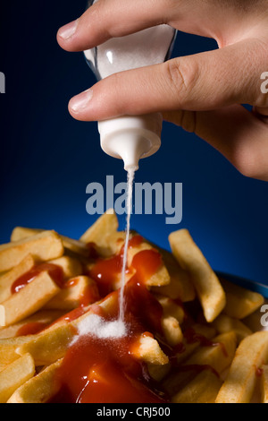 Salz wird auf einem großen Stapel Chips gegossen Stockfoto