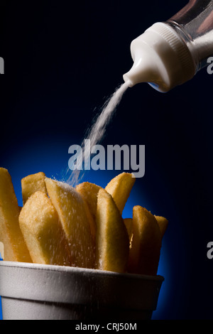 Salz wird auf einer Tasse des Chips gegossen Stockfoto