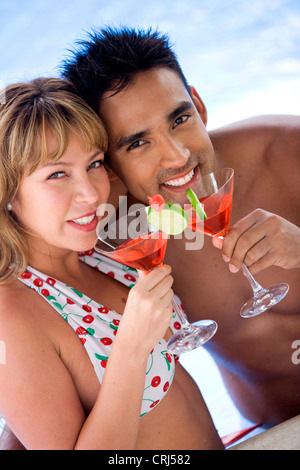 glückliches junges Paar relaxen am Pool, Cocktails genießen Stockfoto