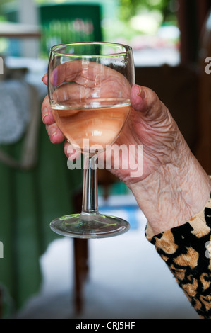 Eine ältere Dame hält ein Glas Weißwein. Stockfoto