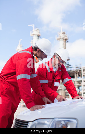 Arbeitnehmer mit Blaupausen an Öl-Raffinerie Stockfoto