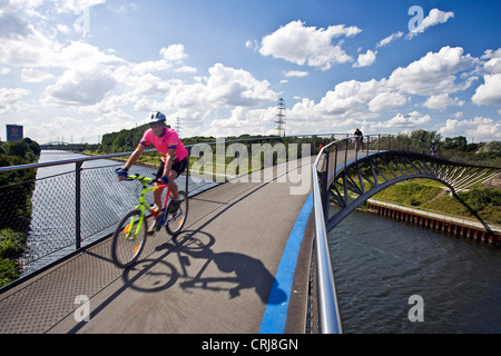 Biker auf einer Brücke über den Rhein-Herne-Kanal, Rhein-Herne-Kanal, in Ripshorst mit Gasometer Oberhausen im Hintergrund, Oberhausen, Ruhrgebiet, Nordrhein-Westfalen, Deutschland Stockfoto