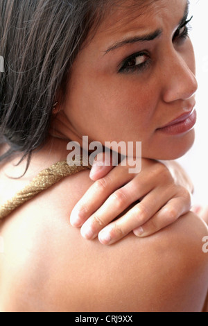 junge Frau hält ihre Schulter mit einem schmerzhaften Blick Stockfoto