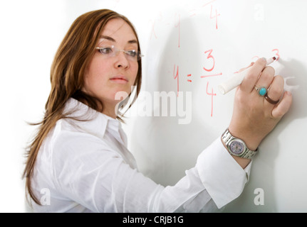 weibliche Lehrer während des Unterrichts Mathematik auf eine Tafel schreiben Stockfoto