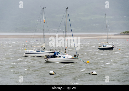 Boote vor Anker in der Bucht an der Mündung des Flusses Mawdach neben The Quay in Barmouth (Abermaw), Wales, sucht Schutz vor den starken Winden aus dem Ozean als Major Regen und Wind vorne bewegt sich durch Wales. Stockfoto