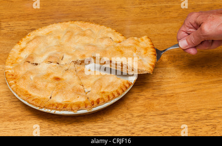 Hand-Stück frisch gebackenen heißen Apfelkuchen auf Holztisch entfernen Stockfoto