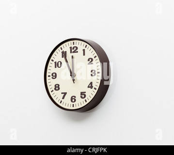 Wanduhr mit fünf Minuten vor 12:00 Stockfoto